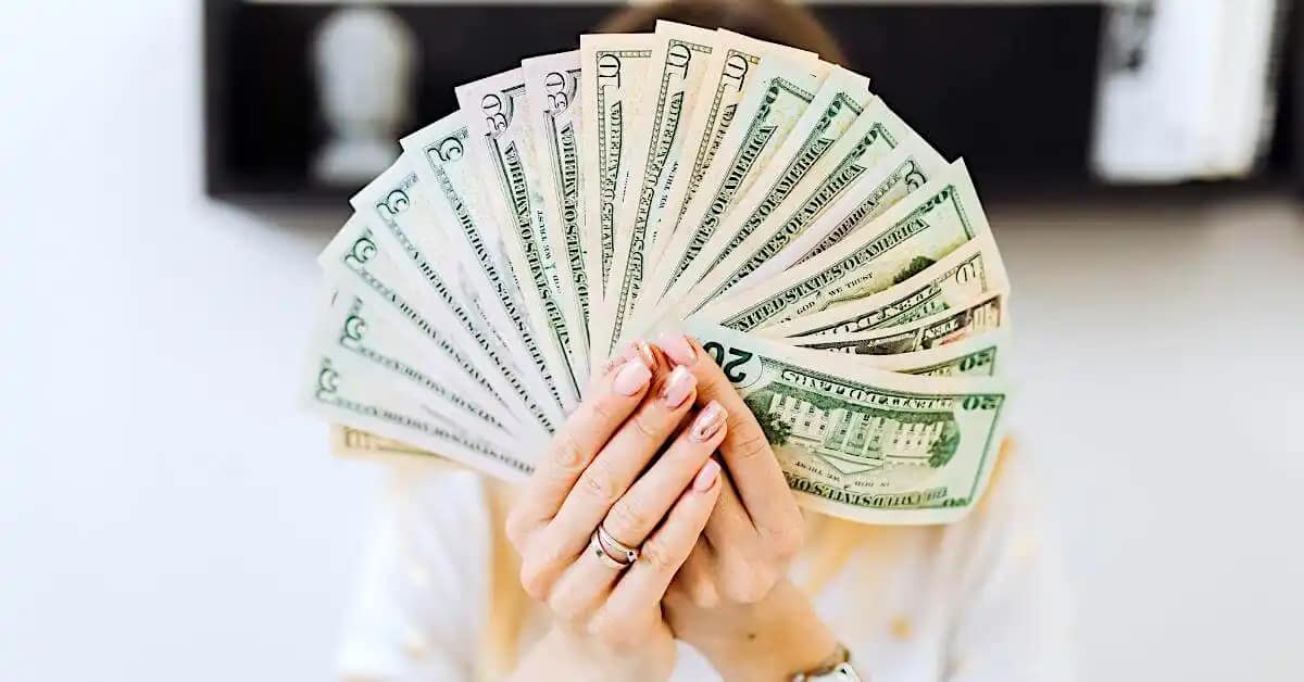 person holding a pile of money face up in their hand showcasing the results of creating residual income