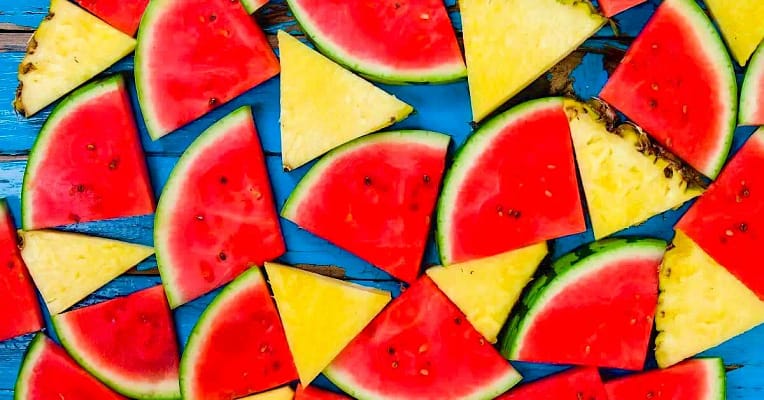 watermelon pineapple-2 slices of pineapple and watermelon on a blue table as an example of one of many tricks that can help with better hydration