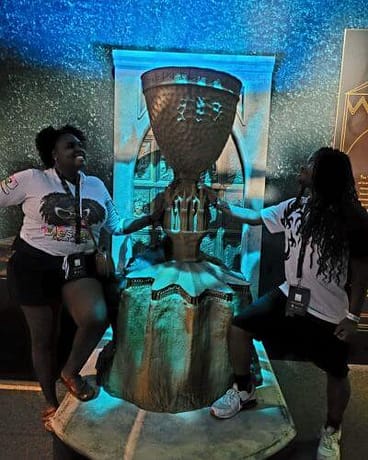 Harry Potter-12-2 a couple standing on either side of a trophy prop at an exhibit posing while looking up with huge smiles.