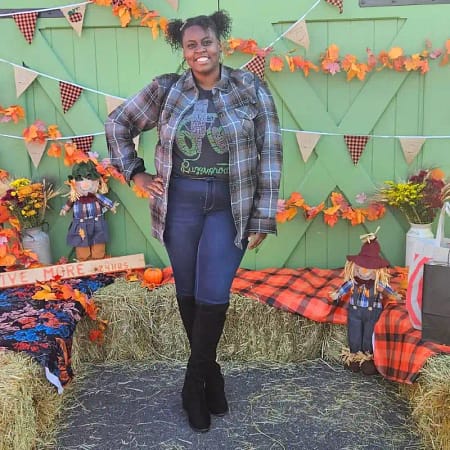 a photo of a  black woman posing in front of fall decorations outside 