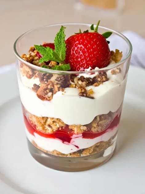 Layered greek yogurt parfait with fresh strawberry, granola, and cream in a glass cup—easy breakfast ideas for quick mornings and simple healthy meals.
