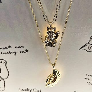 6 A gold necklace featuring a cute cat pendant, and a second gold necklace featuring a dumpling, perfect food jewelry or gift ideas for christmas at the grand opening