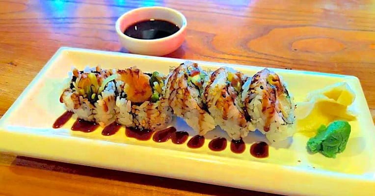 shrimp tempura eel sauce -2-2 a plate of fried shrimp tempura placed in the middle of a table on a white plate drizzled with eel sauce