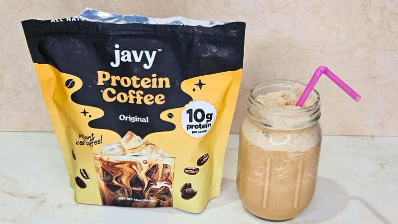 a package of javvy coffee powder placed next to a cold beverage in a glass mason jar