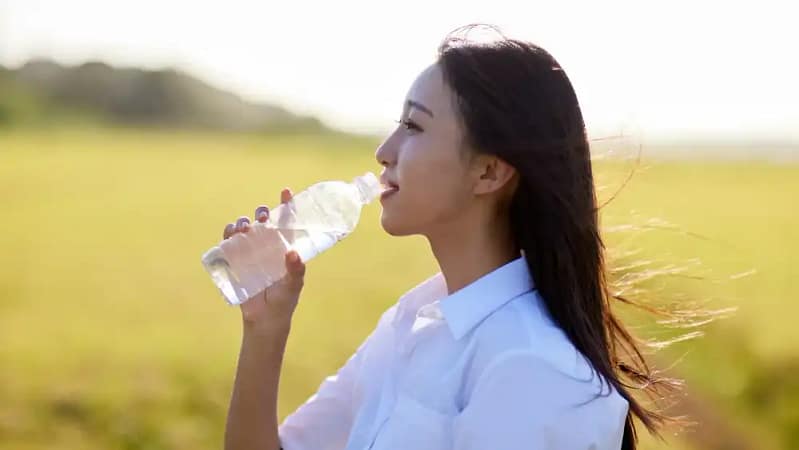 young asian woman with long dark hair holding a bottle of water