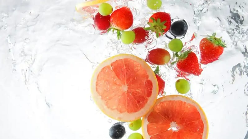 strawberries, grapes, and grapefruit floating in water as one of many hydration hacks