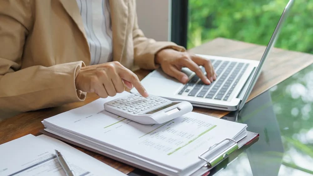 A woman calculates business costs using a calculator, as one of her finance hacks