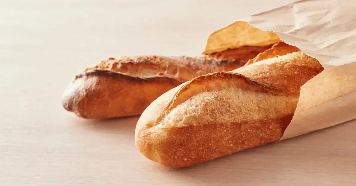Freshly baked baguettes in a paper bread storage bags on a wooden table for optimal budget friendly storage
