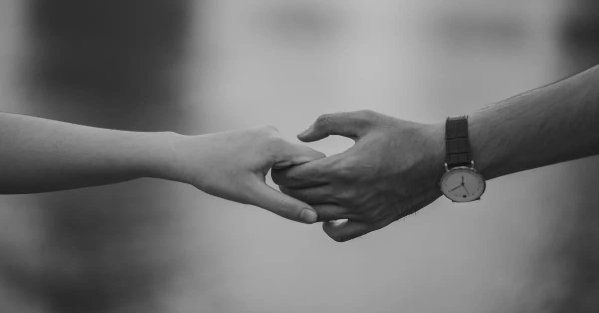 couple finding love unexpectedly while holding hands in a white and black photo with a man wearing a silver or gold watch