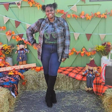 a photo of a black woman posing in front of fall decorations outside