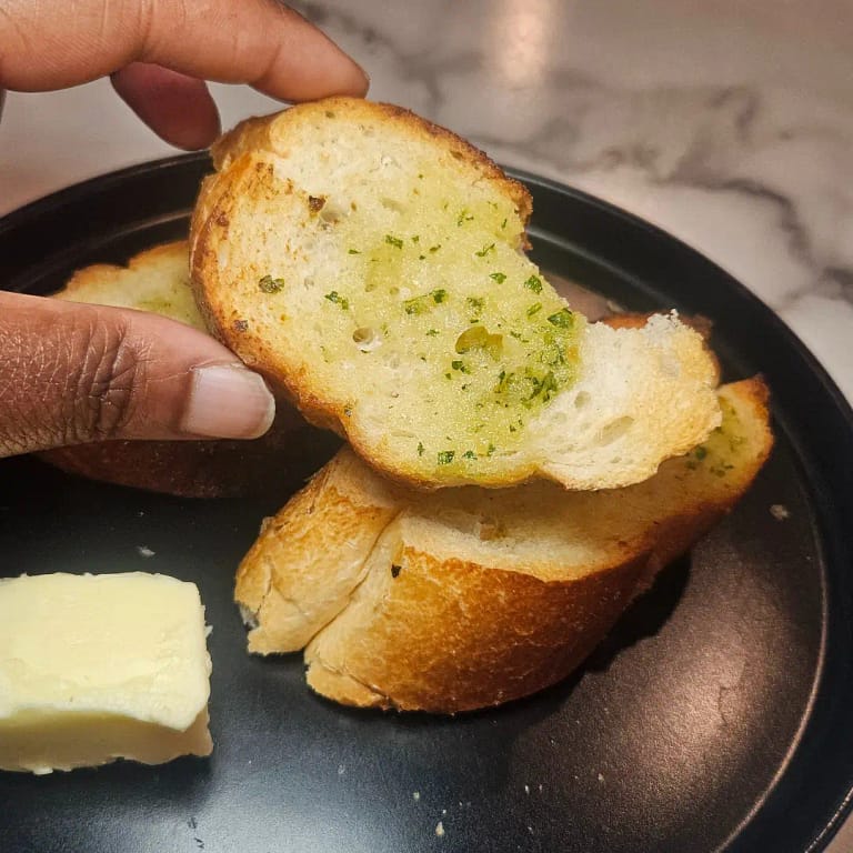 Philly Blogger holding a piece of garlic bread with a nice buttery yellow shine