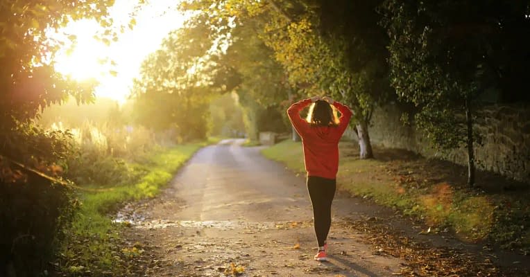 period pain relief A woman stretches on a quiet road, enjoying the fresh air and preparing for her workout in the early morning to help relieve period pain
