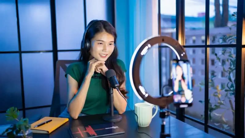 young asian woman creating recurring revenue by filming a video for social media with a ring light